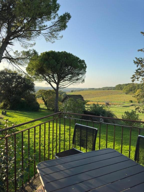 d'une table et de chaises sur un balcon avec vue sur un champ. dans l'établissement Domaine Les Olivoux, à Pomport