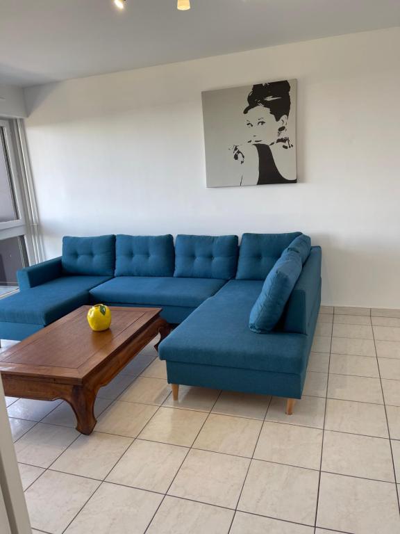 un salon avec un canapé bleu et une table basse dans l'établissement Joli appartement vue tour Eiffel de loin, à Créteil
