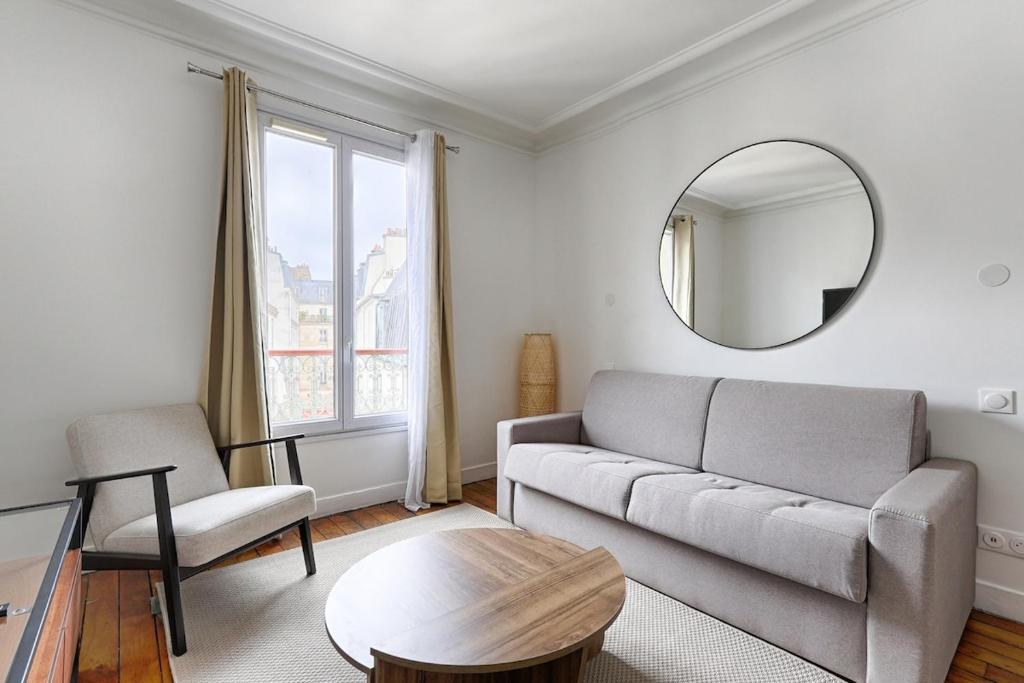 un salon avec un canapé et un miroir dans l'établissement Montmartre Seveste II Beautiful 2BR Apartment, à Paris