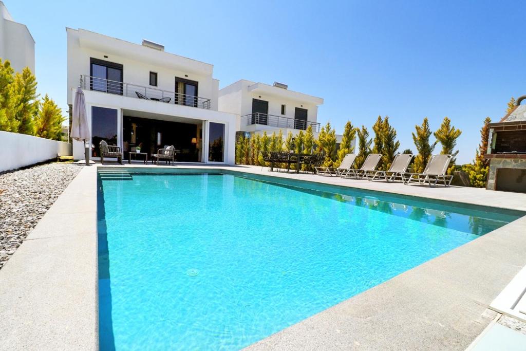 a swimming pool in front of a house at Glaroi 2 in Pefkohori