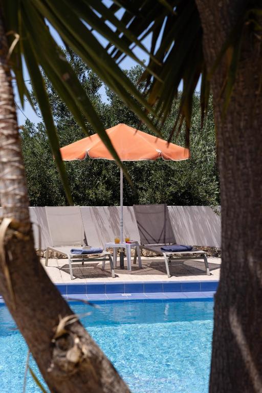 a swimming pool with an umbrella and chairs and a table at Villas Almyrida in Almyrida