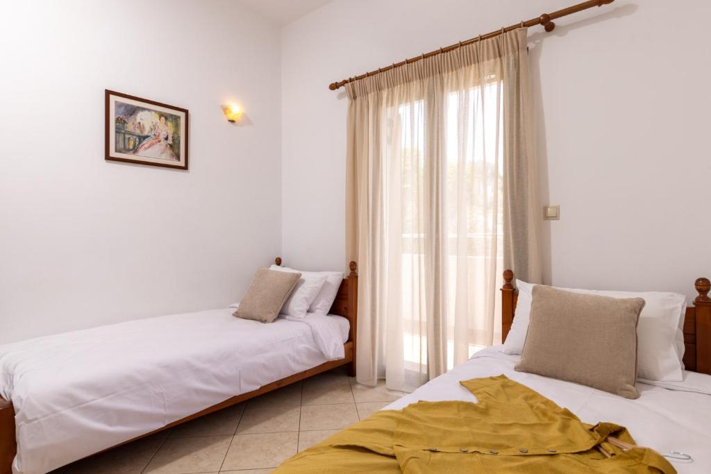 two beds in a room with white walls and a window at Villas Almyrida in Almyrida