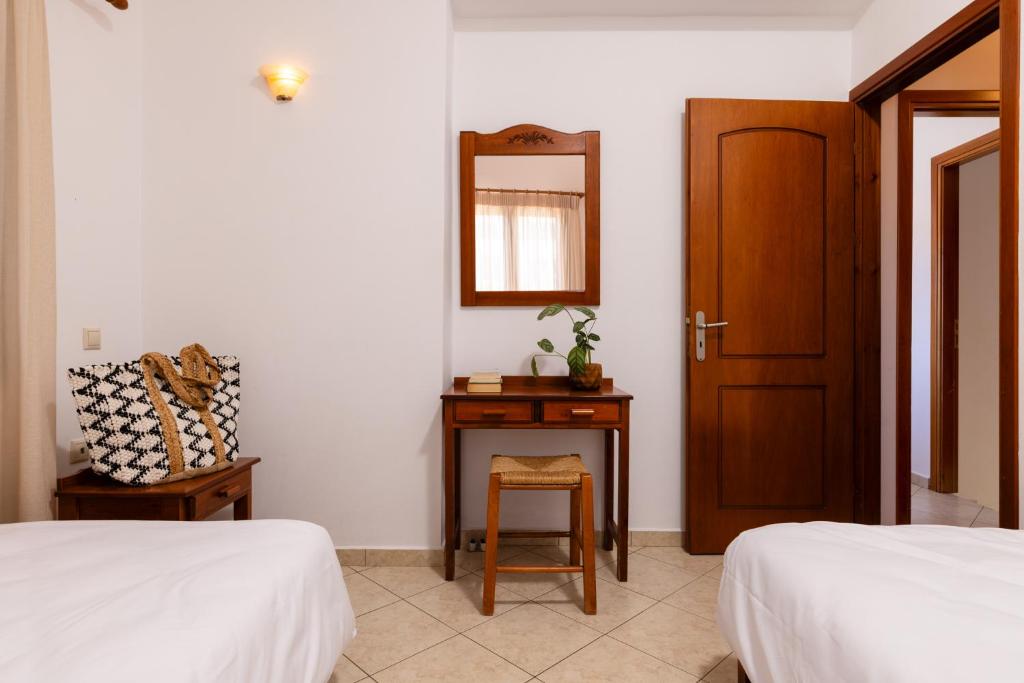 a bedroom with two beds and a mirror and a table at Villas Almyrida in Almyrida
