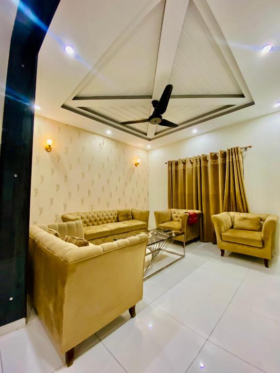 a living room with couches and a ceiling fan at Luxurious Villa In Bahria Town Karachi By Luxus Residencia in Karachi