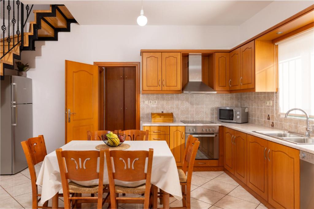 a kitchen with wooden cabinets and a table with chairs at Villas Almyrida in Almyrida