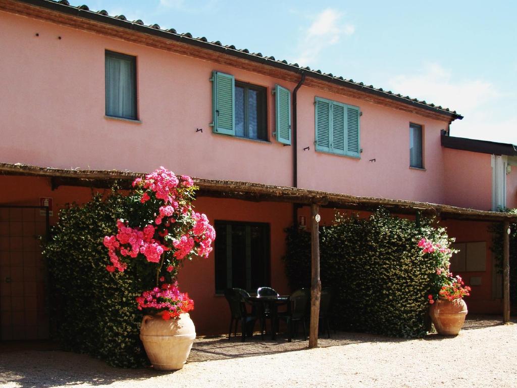 a house with two large vases filled with flowers at Agriturismo Fattoria Il Casalone in Orbetello