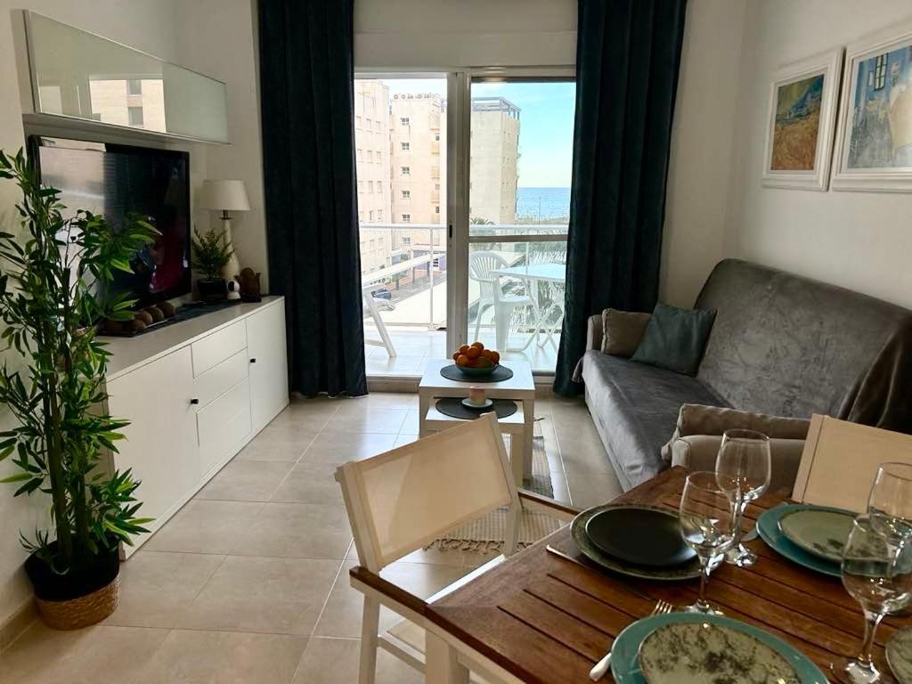 a living room with a couch and a table with wine glasses at Chula Vista Apartamento, 200m de la playa, piscina, parking in Daimuz