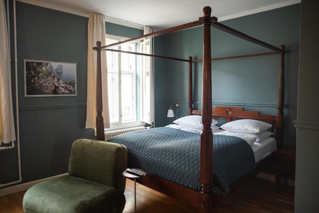 a bedroom with a four poster bed and a chair at SOFS boutique hotel in Aarhus