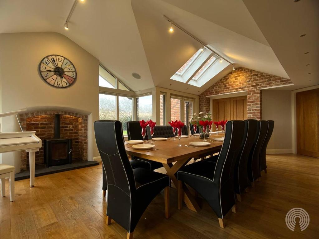 a dining room with a table and a clock on the wall at Welcome To Wrexham - Hot Tub Luxury 5 bed House in Holt
