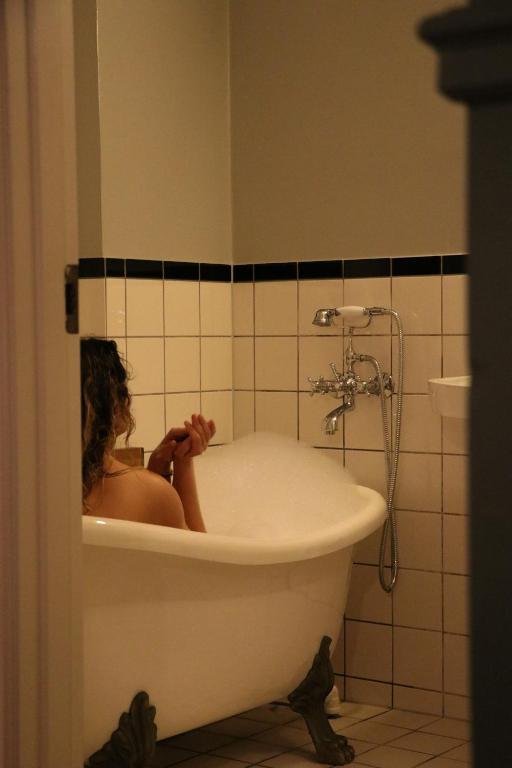 a woman sitting in a bath tub in a bathroom at SOFS boutique hotel in Aarhus