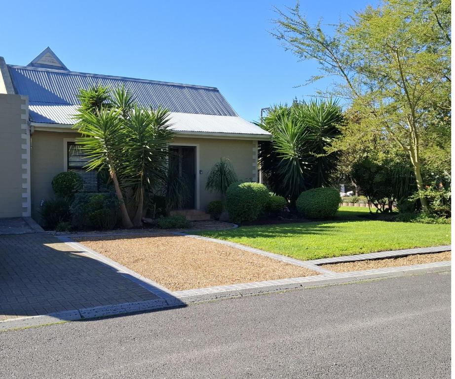 a house with a gravel driveway in front of a house at De Kleine Herberg in Durbanville