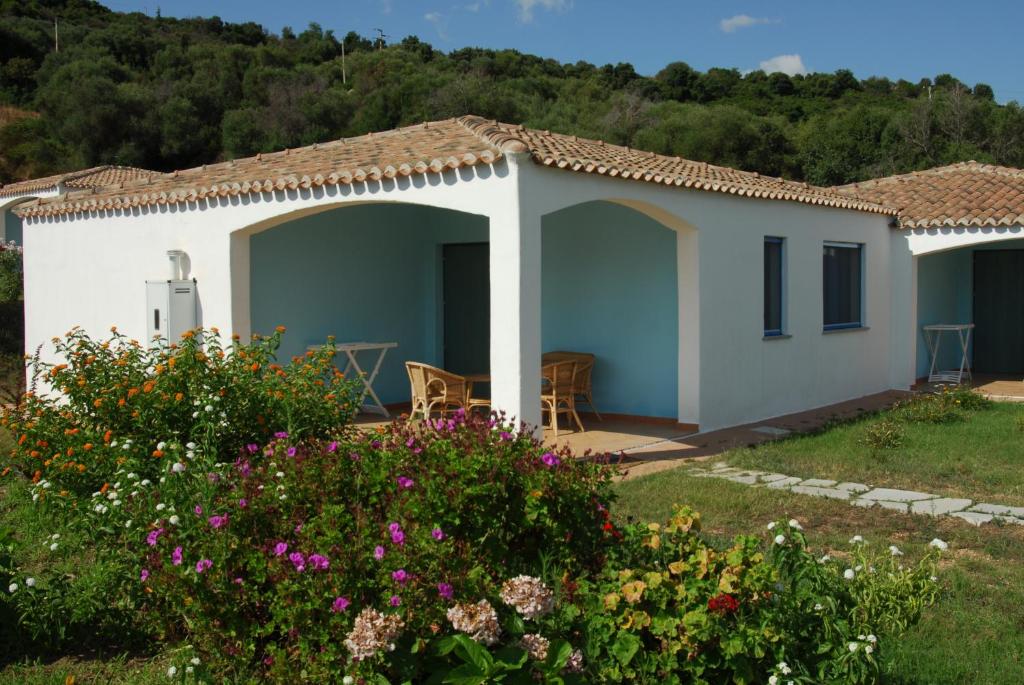 a small white house with a garden and flowers at Hotel Baia Cea in Bari Sardo