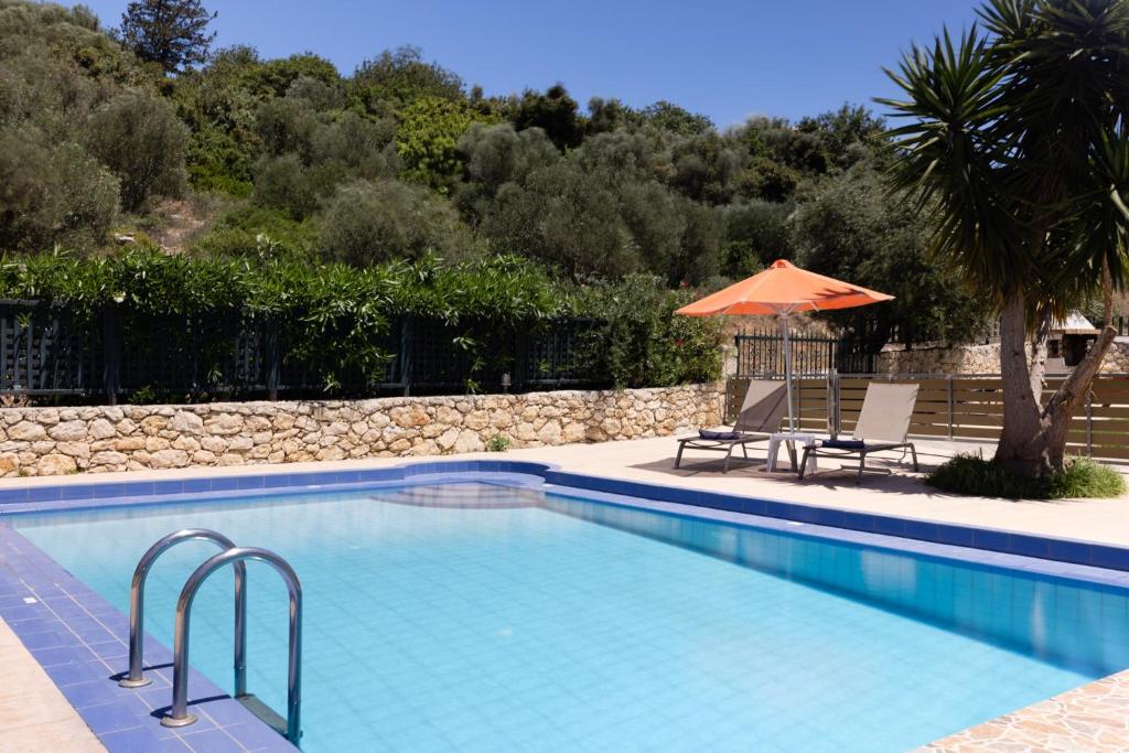 a swimming pool with two chairs and an umbrella at Villas Almyrida in Almyrida