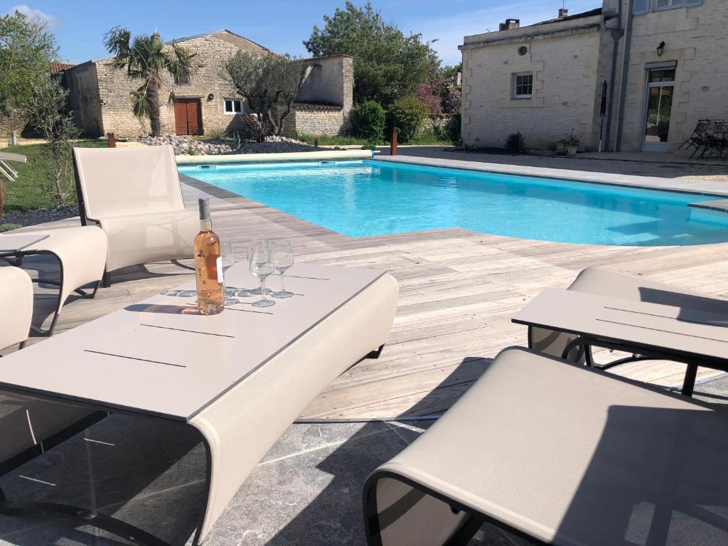 - une table et des chaises à côté de la piscine dans l'établissement Villa Meunière, à Le Bourdet