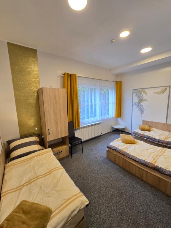 una camera d'albergo con due letti e una finestra di Pokoje gościnne GOOD NIGHT apartamenty, noclegi a Będzin
