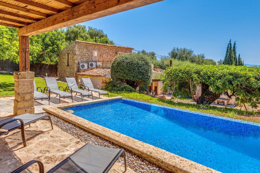 an outdoor swimming pool with chairs and a house at Son Del Rio Nou in Pollença