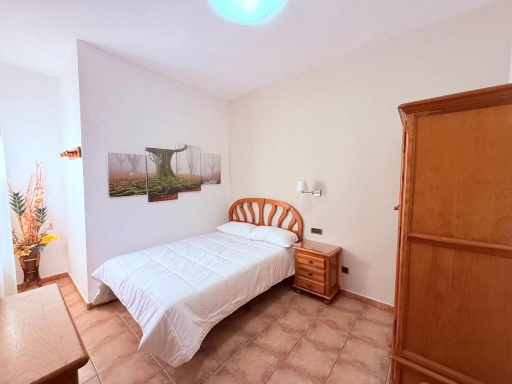 a bedroom with a white bed and a wooden cabinet at Hostal Castilla in Mocejón