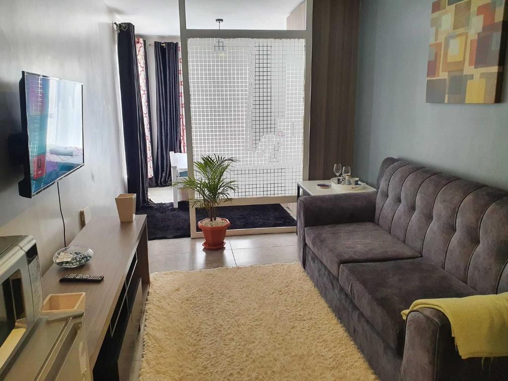 Una sala de estar con un sofá y un televisor. en New Tsavo, en Gatunga