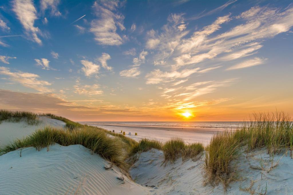a sunset over the sand dunes at the beach at Hotel Atlantic Juist in Juist