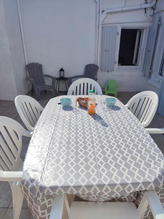 une table blanche entourée de chaises blanches dans l'établissement Maison de vacances ile d'Oléron 4 pers à St Denis proche plage, à Saint-Denis-dʼOléron