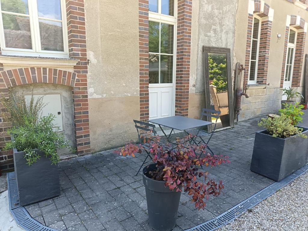 a patio with a table and potted plants in front of a building at Gîte L'instant Ressource pour rassemblement familial ou entre amis au coeur de la Puisaye Forterre in Villiers-Saint-Benoît