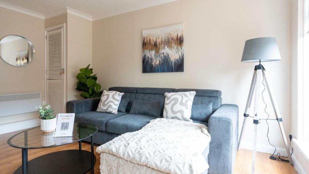 a living room with a blue couch and a glass table at Forbes House in Glasgow