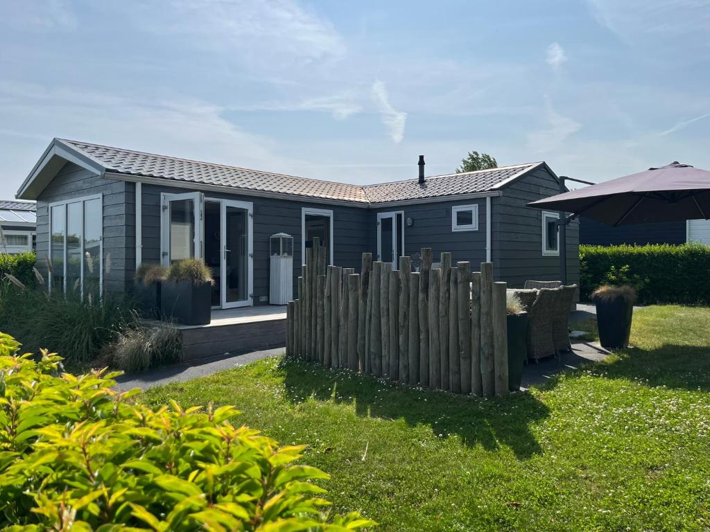 a house with a wooden fence in front of it at Sfeervol chalet op familiepark in Oostkapelle vlakbij strand in Oostkapelle