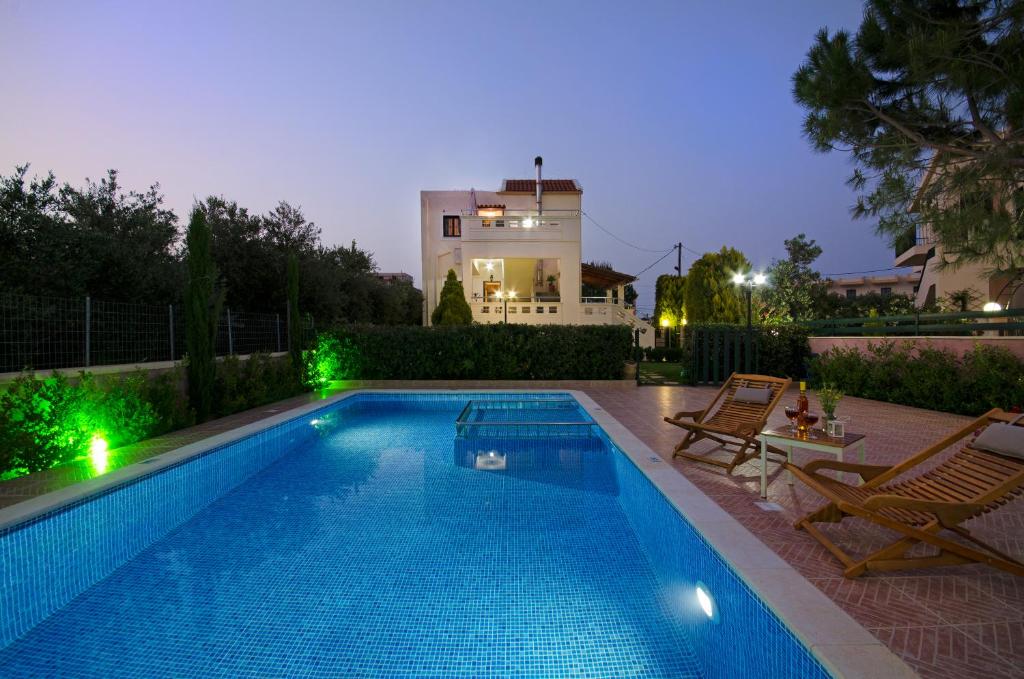 a swimming pool with two chairs and a house at Villa Alimedon in Almirida