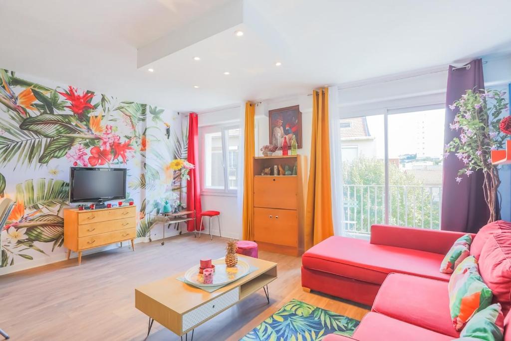 un salon avec un canapé rouge et une télévision dans l'établissement United Colors Of Clermont, à Clermont-Ferrand