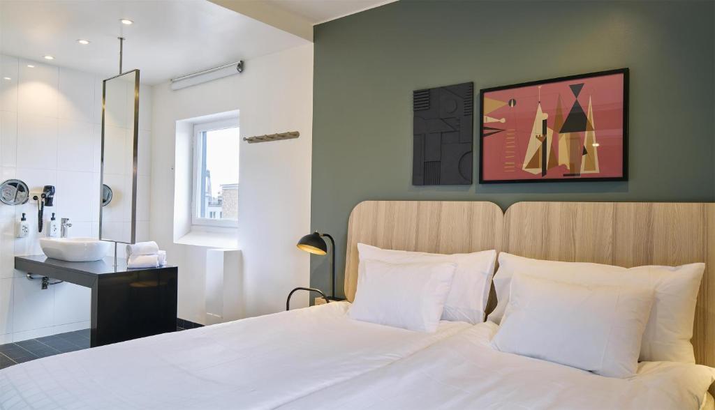 a bedroom with a white bed and a sink at Scandic Malmen in Stockholm