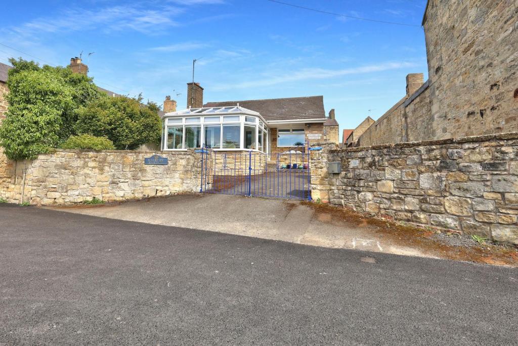 un mur de pierre et une maison avec un portail dans l'établissement Riverview Cottage - North East Escapes, à Warkworth