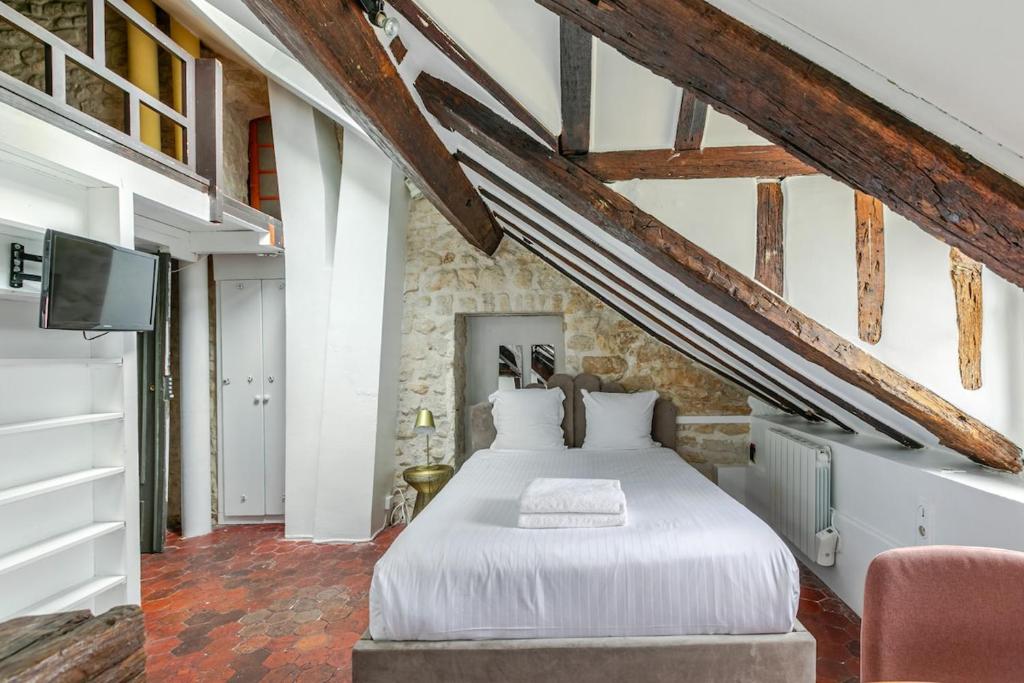 - une chambre avec un lit blanc dans un mur en pierre dans l'établissement Studio sous les poutres à Paris, à Paris
