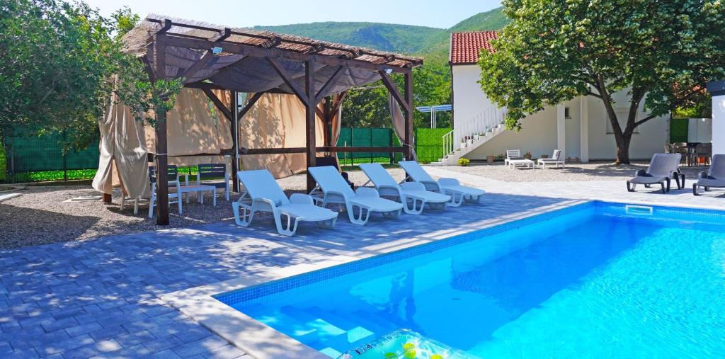 a swimming pool with chairs and a gazebo at Twins Land in Mostar
