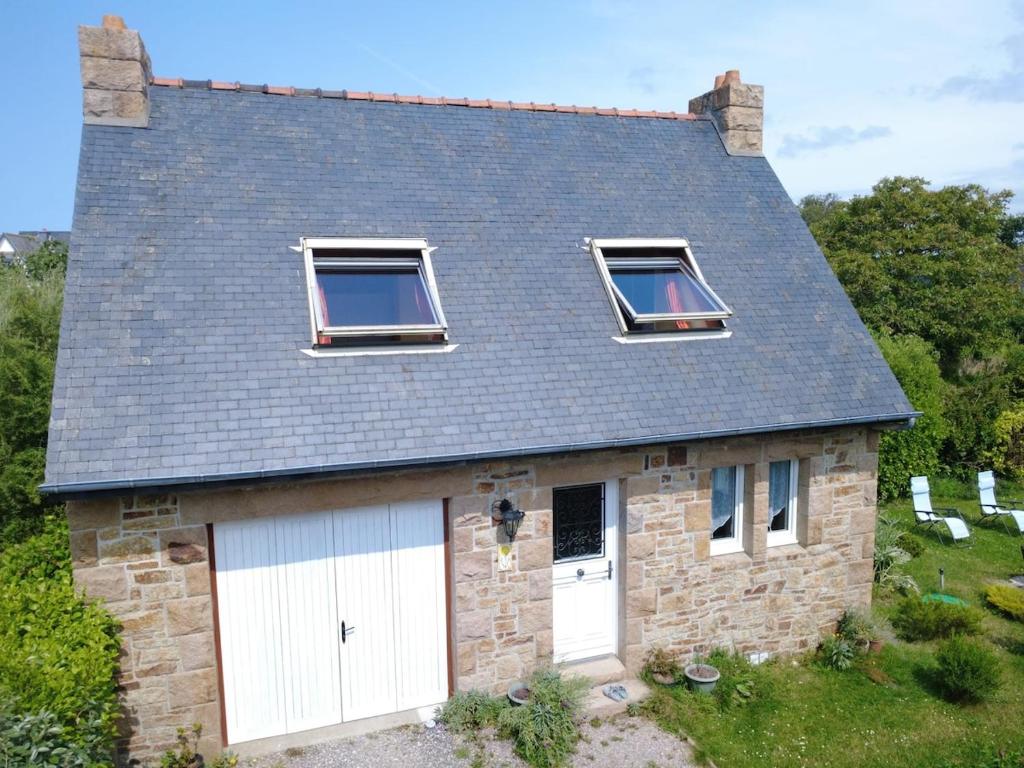 une maison en pierre avec trois fenêtres et un toit dans l'établissement TY ROZ beau gîte tout rénové en bord de mer, à Perros-Guirec