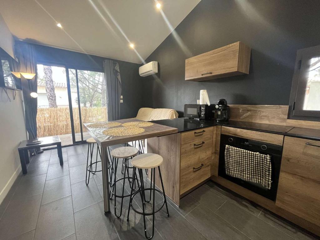 une cuisine avec un comptoir, une table et des tabourets dans l'établissement Appartement T2 avec piscine et parking, Cap d'Agde - FR-1-249-430, au Cap d'Agde