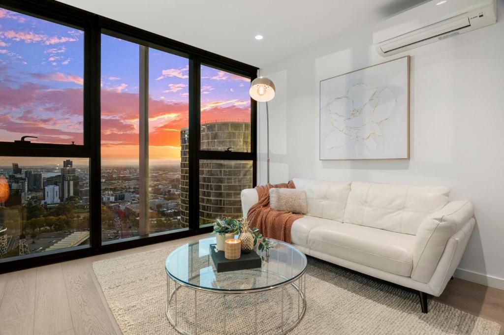 sala de estar con sofá blanco y mesa de cristal en Impressive City Skyline w Pool Gym & Sauna, en Melbourne