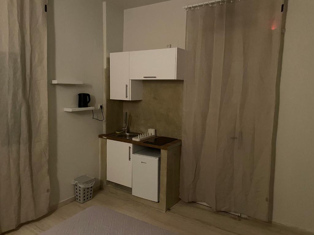 a small kitchen with white cabinets and a curtain at Villa Sylvia in Matala