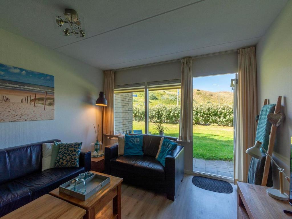 a living room with a couch and a glass door at Beach Apartment 7 for 4 guests in Callanstoog in Callantsoog