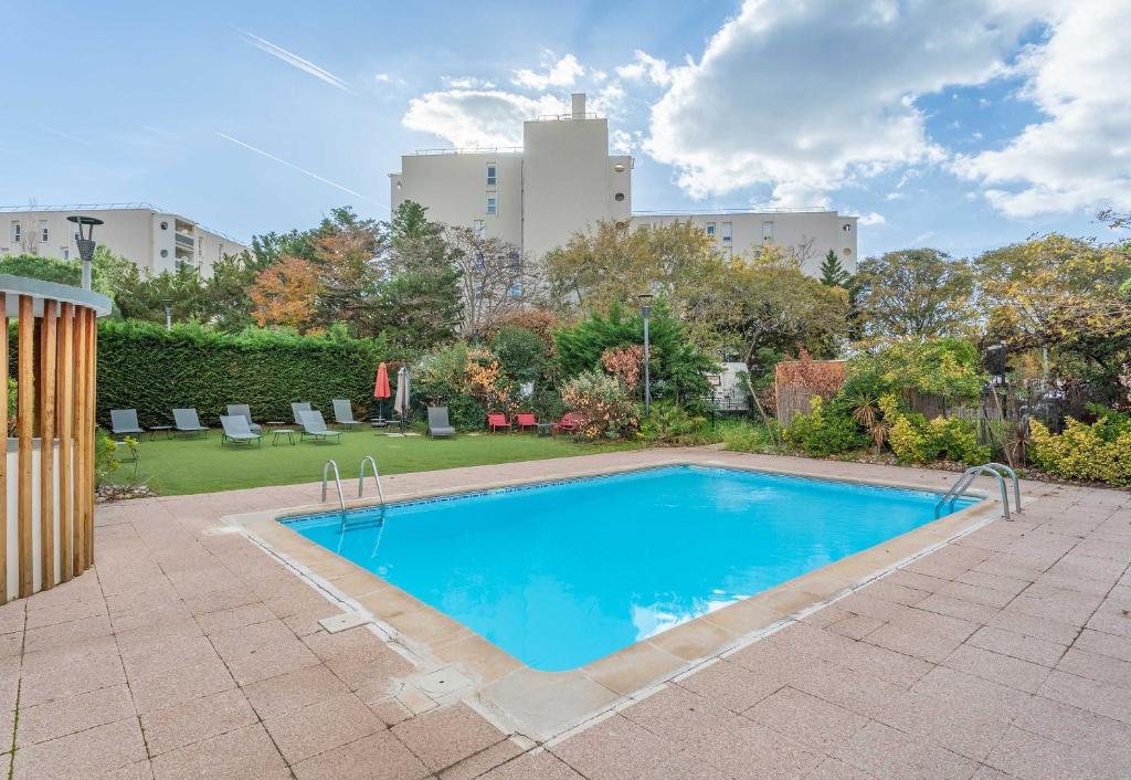 une piscine dans une cour avec un bâtiment en arrière-plan dans l'établissement B&B HOTEL Marseille Bonneveine, à Marseille