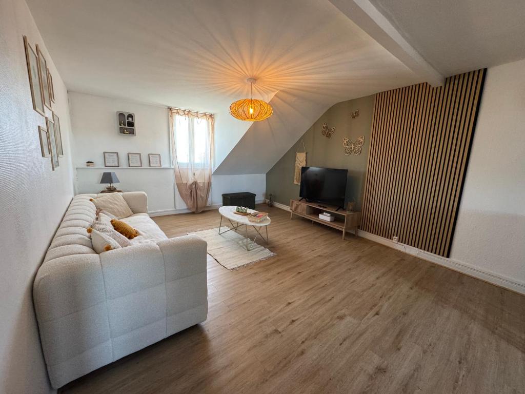 a living room with a white couch and a television at Au pays des bretzels in Horbourg