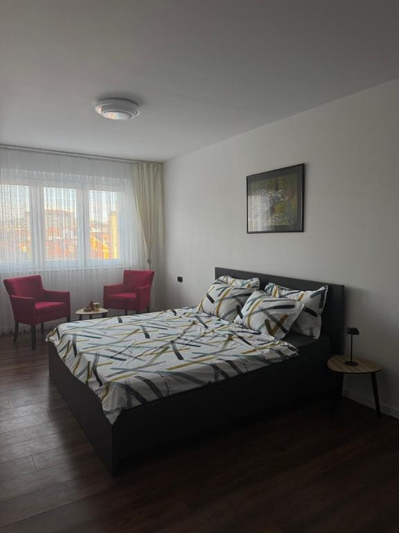 a bedroom with a bed and two red chairs at Nick Apartment in Pristina