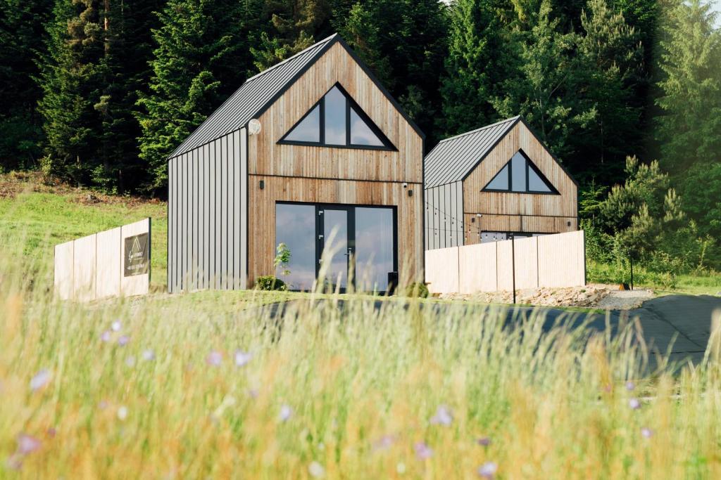 a wooden house in a field with trees at Łyse Stodoły in Mordarka