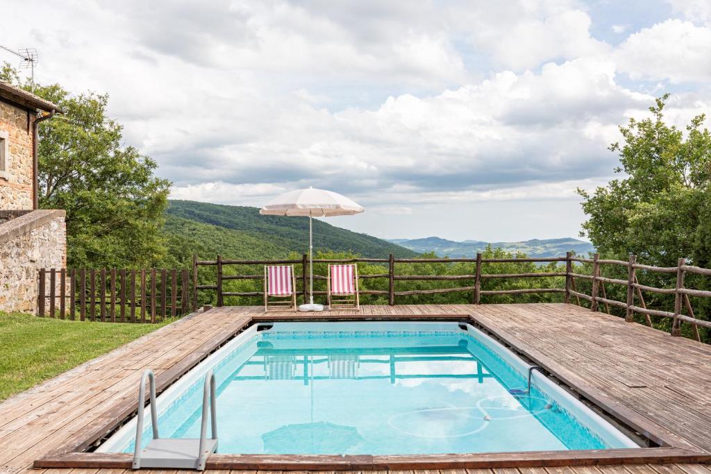 a swimming pool with a deck and an umbrella at Masseria del bosco Palazzone in Chianciano Terme