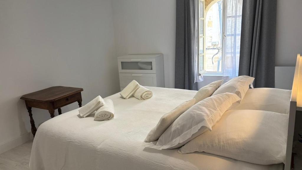 Un dormitorio con una cama blanca con almohadas y una ventana. en Cosy loft in Saint Emilion, en Saint-Émilion