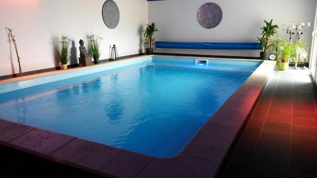 a large swimming pool with blue water in a room at Le Miroir des Etoiles in Pomport