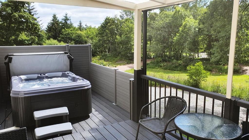 - un bain à remous sur une terrasse avec une table et des chaises dans l'établissement River Cottage Hot tub spa, à Drumnadrochit