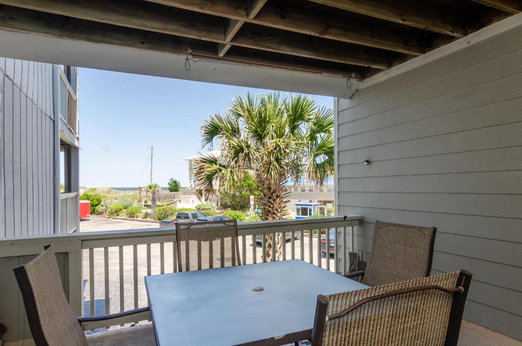 a porch with a table and chairs on a balcony at Hook, Line and Two Stinkers by Bryant Real Estate in Carolina Beach