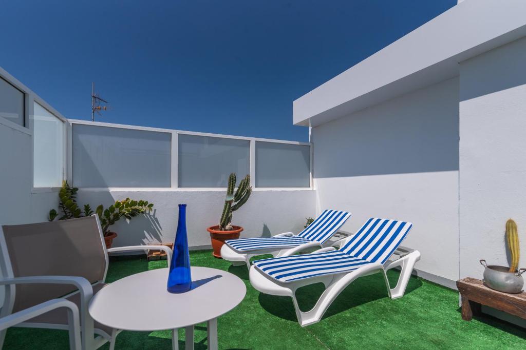 a patio with two chairs and a table and some plants at Home2Book Bright Retreat with Roof Access in Vecindario