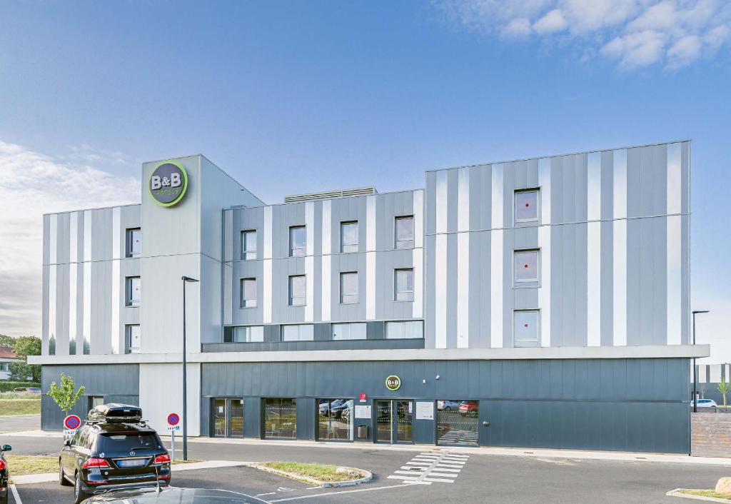 a building with a car parked in front of it at B&B HOTEL Poitiers Aéroport in Poitiers