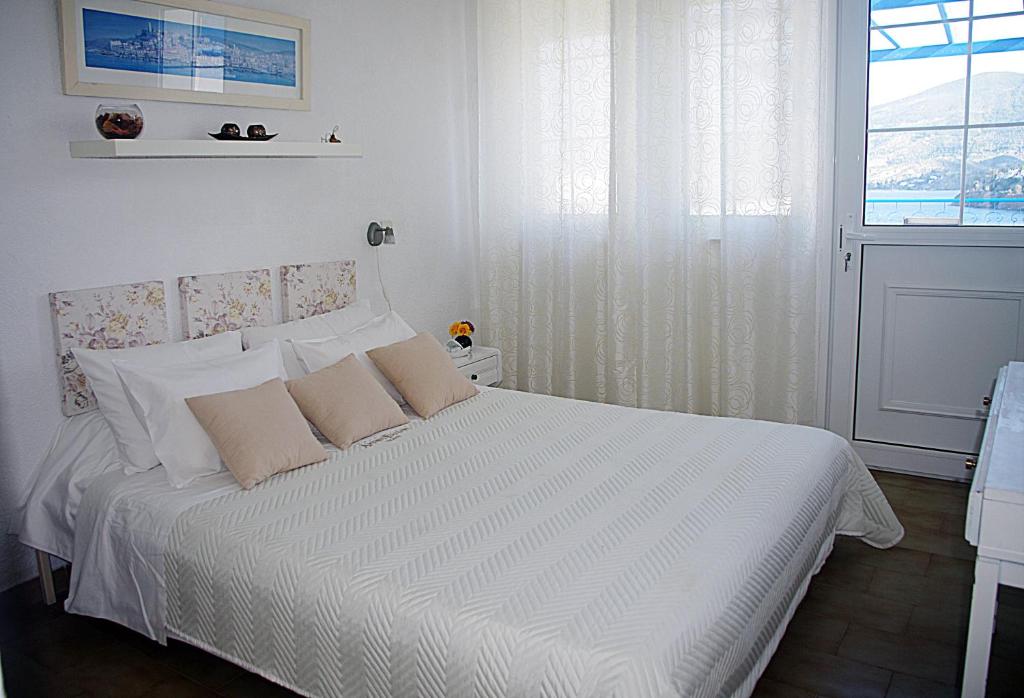 a bedroom with a bed with white sheets and a window at Rania Studios in Poros